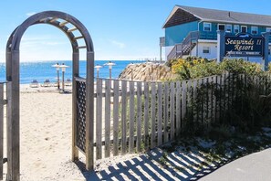Une entrée sécurisée donnant accès au complexe hôtelier Seawinds II, avec une vue dégagée sur la plage et l’océan.