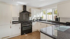 Een moderne keuken met witte kasten, een zwart fornuis en een groot raam.