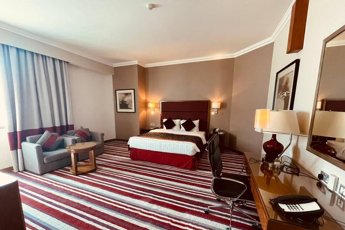 Une chambre d’hôtel équipée d’un lit, d’un canapé, d’un bureau, d’une chaise, d’un téléphone et d’une lampe.