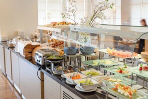 Buffet com diversos alimentos e um expositor de vidro.