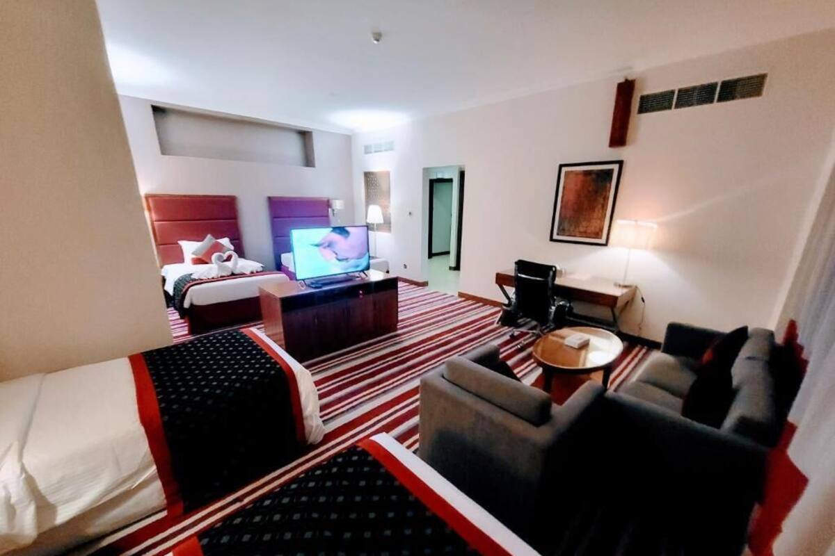 Une chambre d’hôtel avec un lit, un canapé, une télévision, un bureau et une chaise.