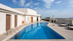 A rooftop swimming pool with a clear blue sky, a lifeguard stand, and lounge chairs. - Wonder Palace Hotel Qatar (Doha)
