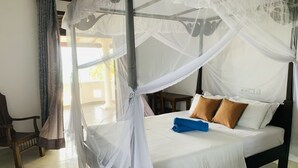 Una habitación con cama bajo un dosel, una silla y vistas al exterior.