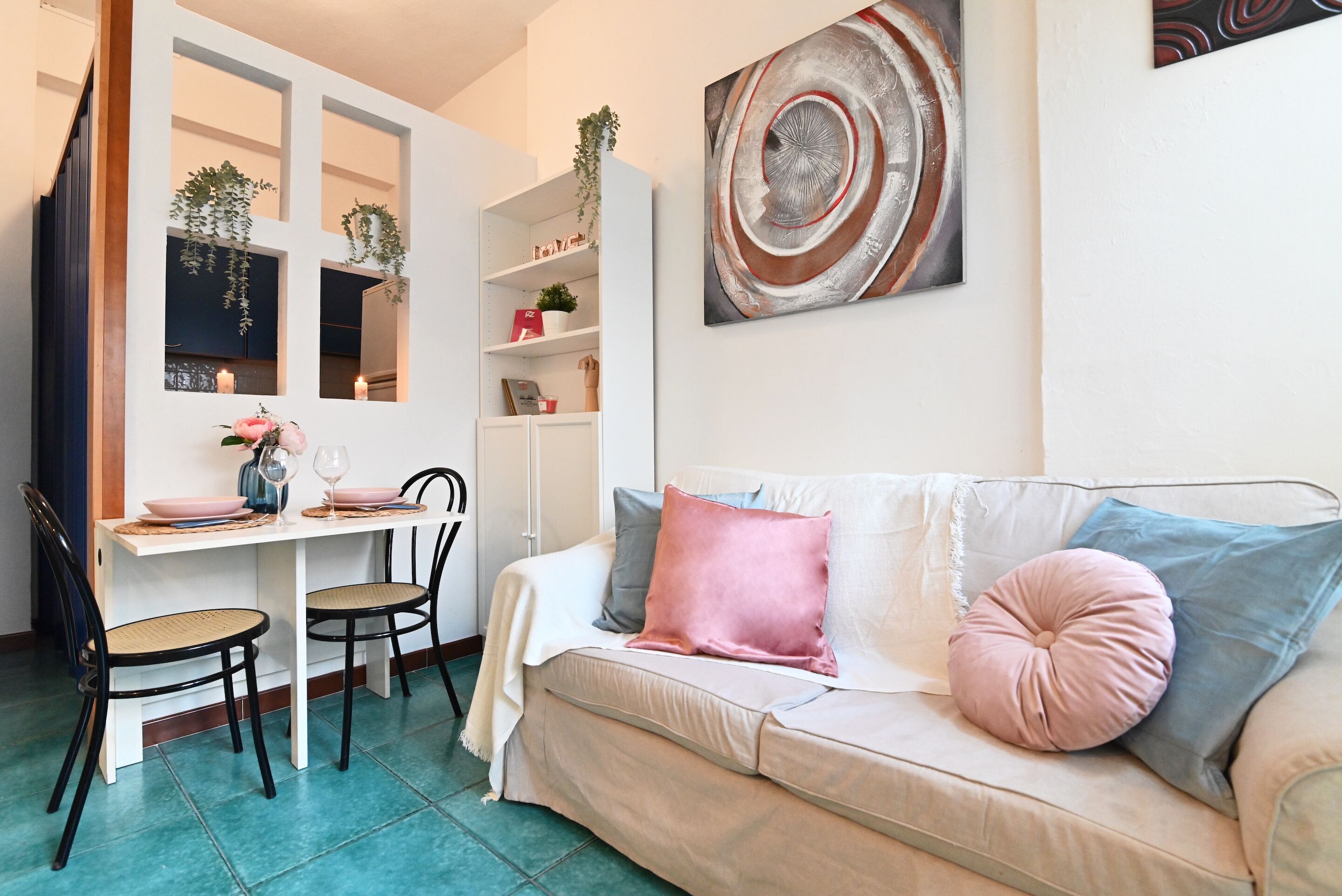 A cozy living room with a sofa, a dining table with chairs, and a bookshelf.