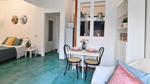 A compact living space with a dining area, a bed, and a kitchenette. - IzzHome City Love (Cagliari)