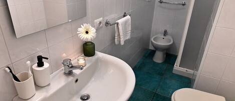 A bathroom with a white sink, a bidet, and a toilet.