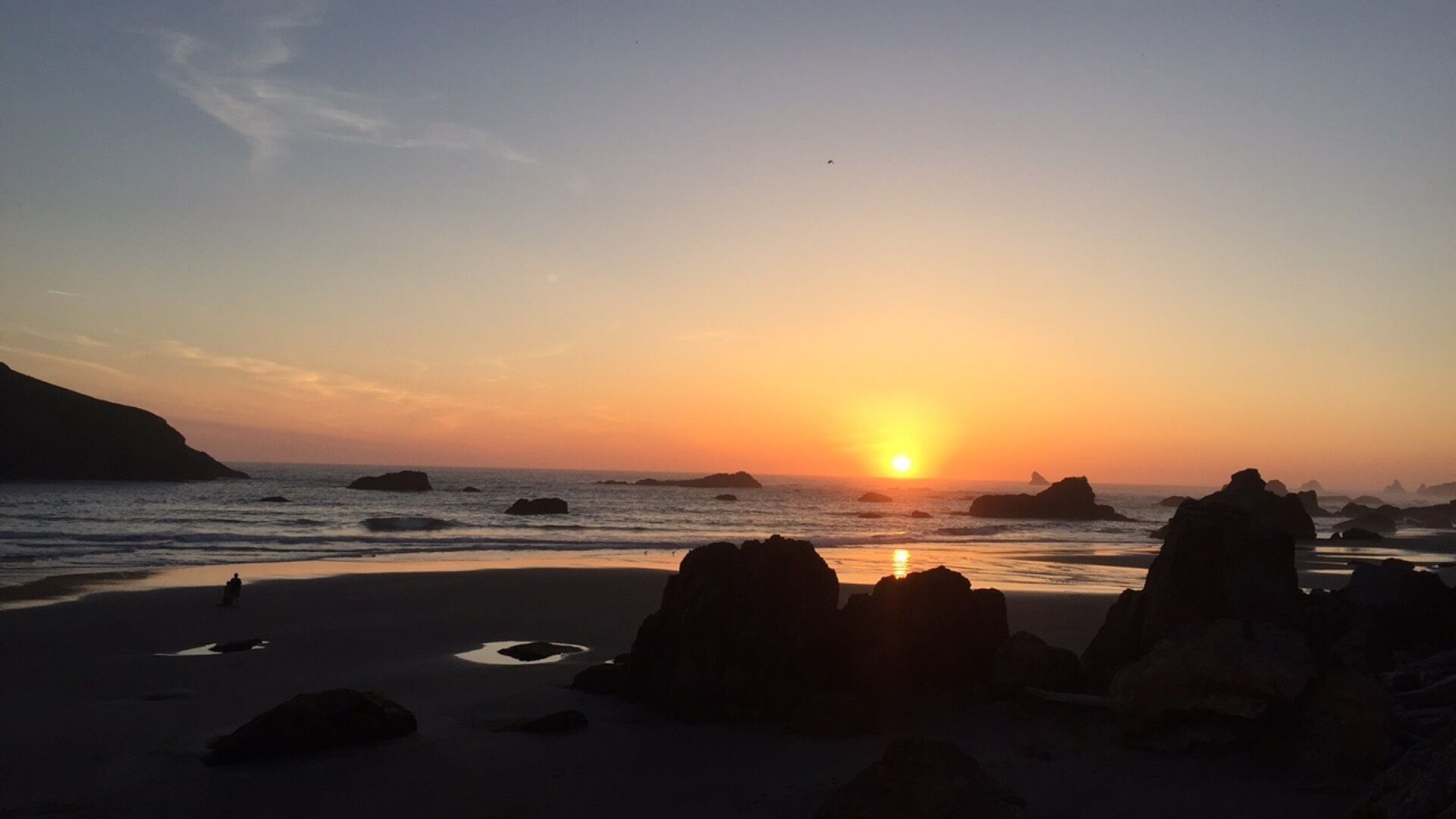 A beach with large rocks and a sunset.