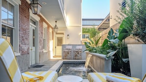 A spa area with a small pool, two lounge chairs, and a table.