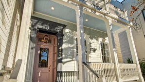 A two-story house with a front porch, a pink door, and a white railing.