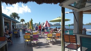 An outdoor dining area with colorful chairs and umbrellas, overlooking a body of water. - Sunset Lagoon. In the heart of Hudson. Waterfront. 2 minute walk beach/dining (Hudson)