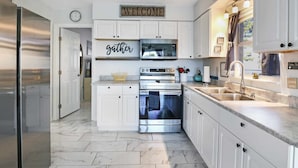 A modern kitchen with white cabinetry, a stainless steel refrigerator, a microwave, an oven, and a sink. - Sunset Lagoon. In the heart of Hudson. Waterfront. 2 minute walk beach/dining (Hudson)