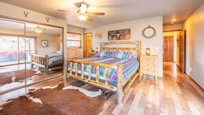 Un dormitorio con cama de madera, ventilador de techo y alfombra de cuero de vaca.