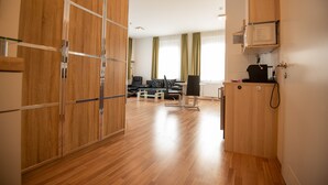 Una moderna camera d'albergo con pavimento in legno, un'area pranzo con tavolo e sedie e un angolo cottura con forno a microonde.