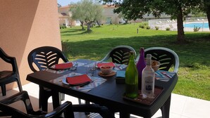 An outdoor dining table set with chairs, a bowl of fruit, and two bottles of water. - 3-star ANCV-approved house in a lovely condominium (SANTA MARIA POGGIO)