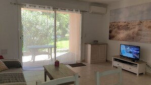 A room with a bed, a table, a TV, and a sliding glass door leading to an outdoor area. - 3-star ANCV-approved house in a lovely condominium (SANTA MARIA POGGIO)