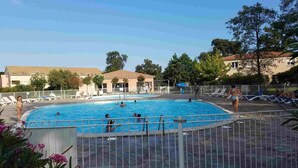 A swimming pool with a fenced area, lounge chairs, and a building in the background. - 3-star ANCV-approved house in a lovely condominium (SANTA MARIA POGGIO)