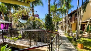 A pathway lined with palm trees and a metal railing, leading to a building with a balcony. - Hotel e Pousada Sonho Meu (Florianópolis)