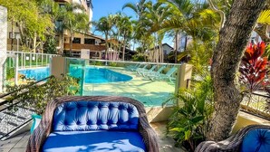 A pool area with lounge chairs, a wicker sofa, and a view of a residential building. - Hotel e Pousada Sonho Meu (Florianópolis)