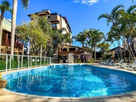Una piscina circondata da palme e un edificio a più piani con balconi.