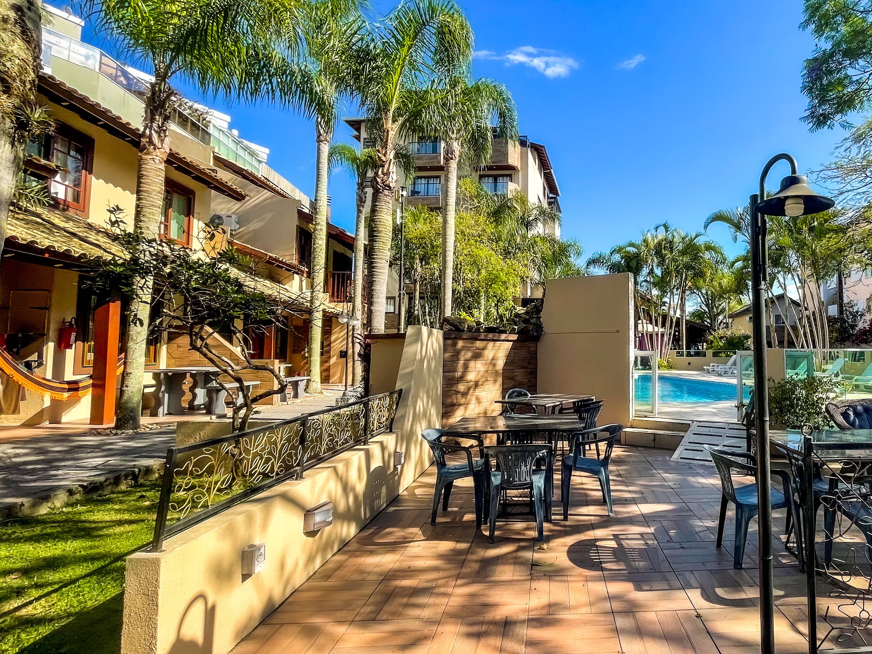 Zona de piscina con mobiliario exterior y vistas a un edificio con varios balcones.