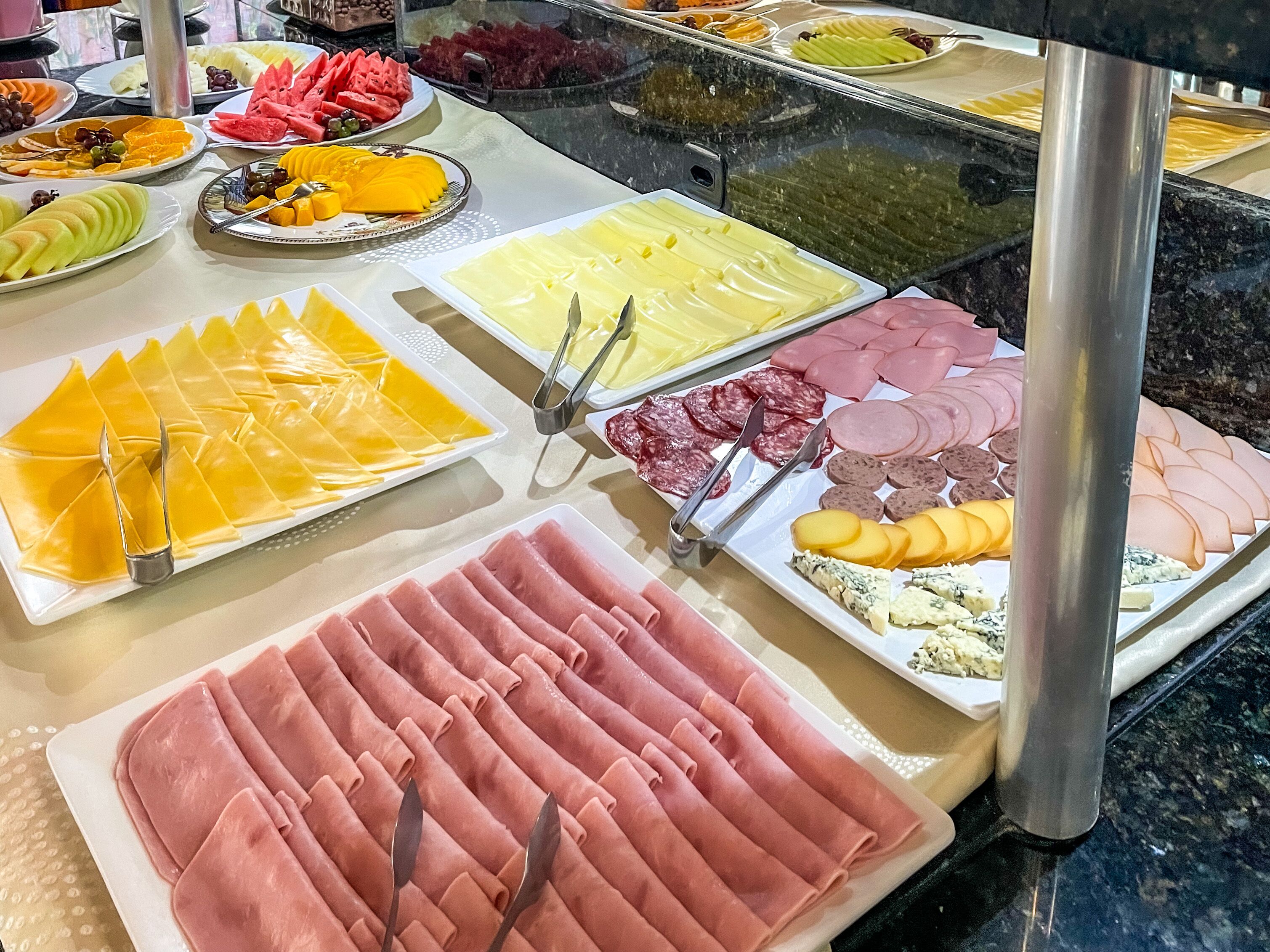 Un bufé con distintos alimentos, como embutidos, quesos y frutas.