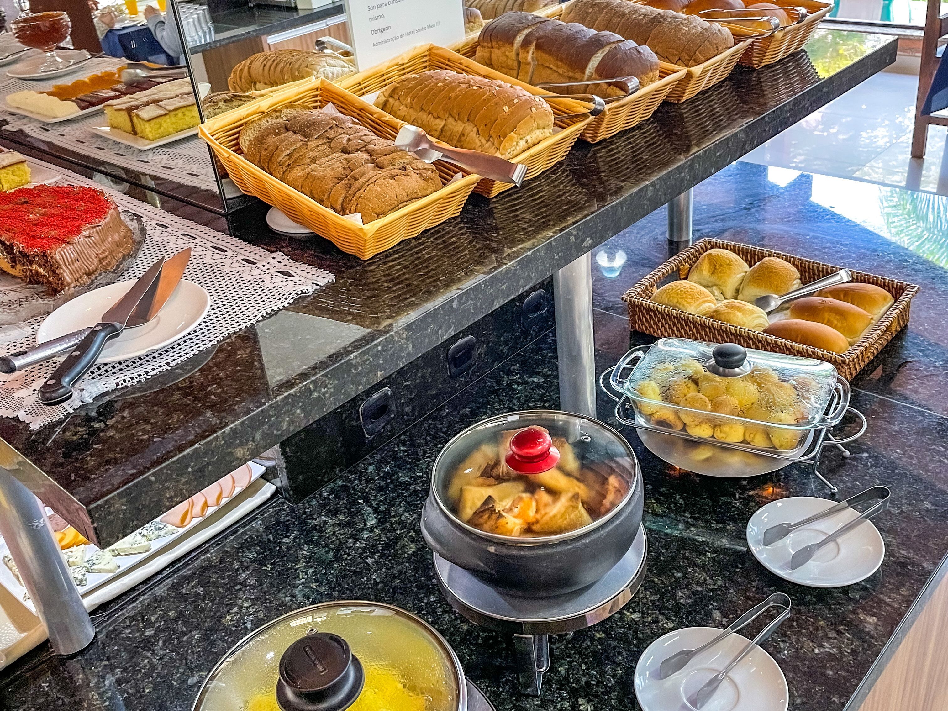 Een ontbijtbuffet met verschillende broden, gebak en een soepketel.