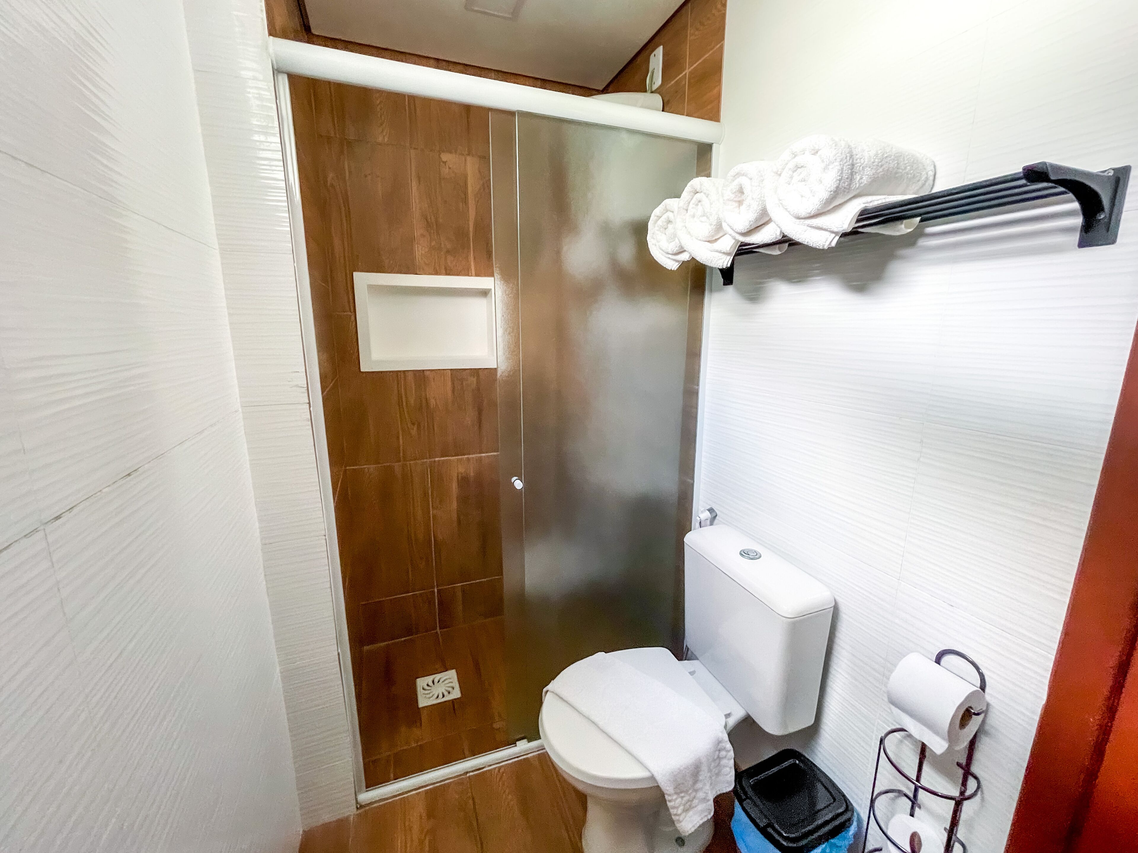A bathroom with a shower, toilet, and towel rack.