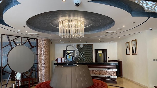 A modern lobby with a central round table, a chandelier, and a reception desk. - Palm Inn Hotel Doha (Doha)