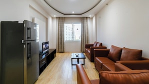 A compact living space with a kitchenette, a brown leather sofa, a small table, and a window with curtains. - Palm Inn Hotel Doha (Doha)
