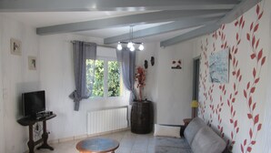 A living room with a sofa, a small table, a television, and a window with curtains.