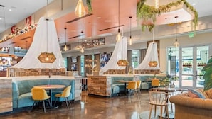 Um restaurante moderno com cabines e mesas, um espaço de bar e plantas penduradas.