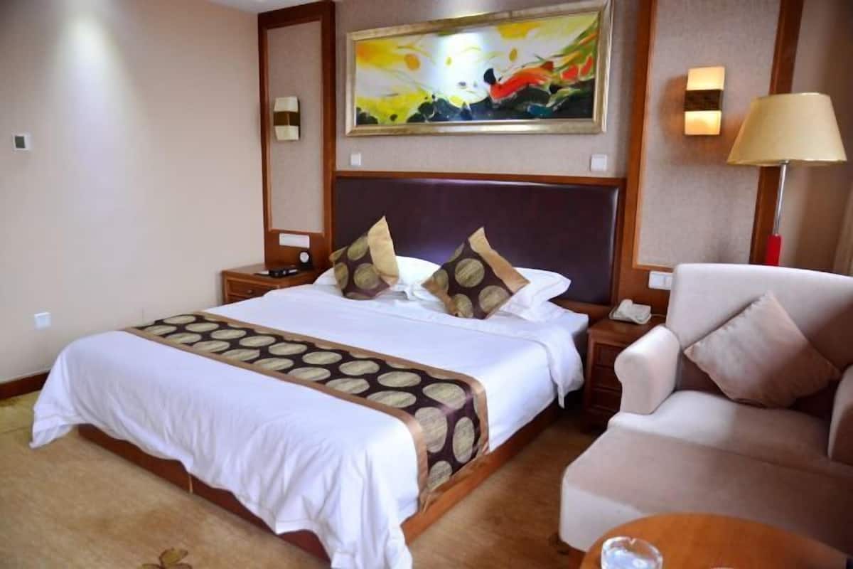 Ein Hotelzimmer mit einem großen Bett, einer Couch, einem Nachttisch mit Lampe und einem Bild an der Wand.