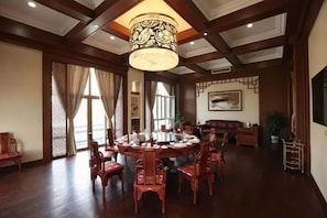 A traditional dining room with a round table, wooden chairs, and a hanging light fixture. - Haiyi Hotel Xueye (Jinan)
