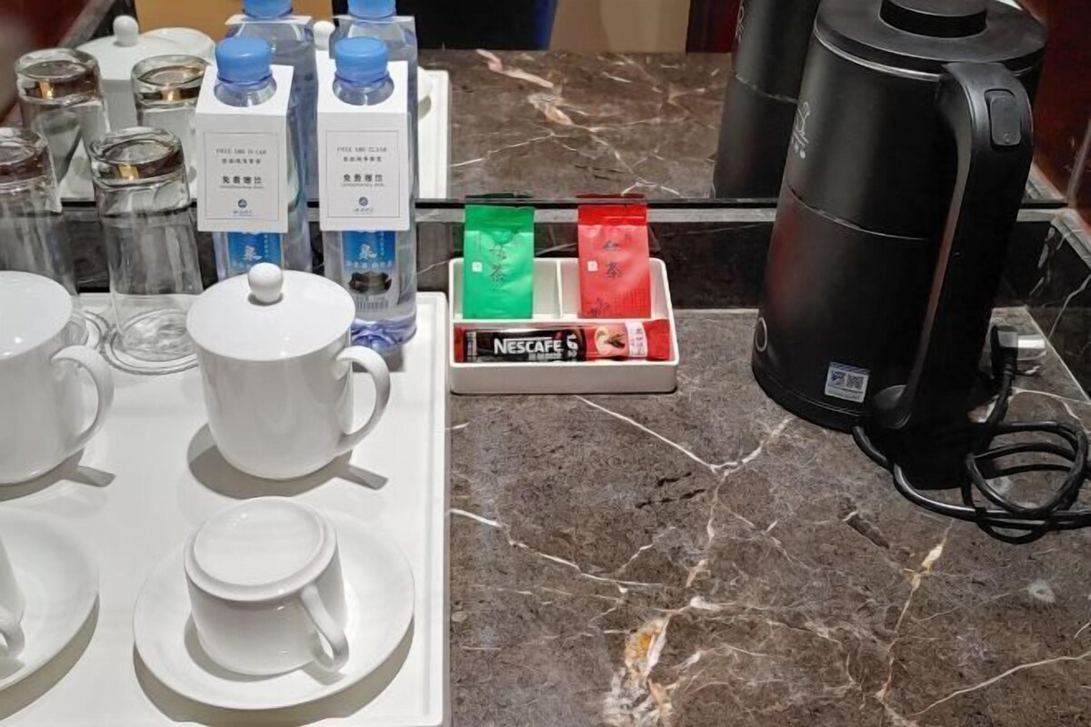 A kitchen area with a coffee machine, a coffee pod dispenser, and a marble countertop.