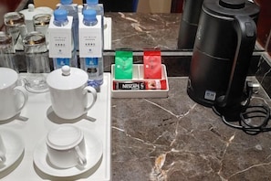 A kitchen area with a coffee machine, a coffee pod dispenser, and a marble countertop.