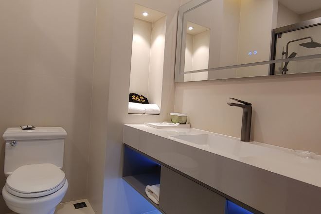 A modern bathroom with a toilet, a sink, a mirror, and a shower area.