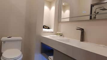 A modern bathroom with a toilet, a sink, a mirror, and a shower area.