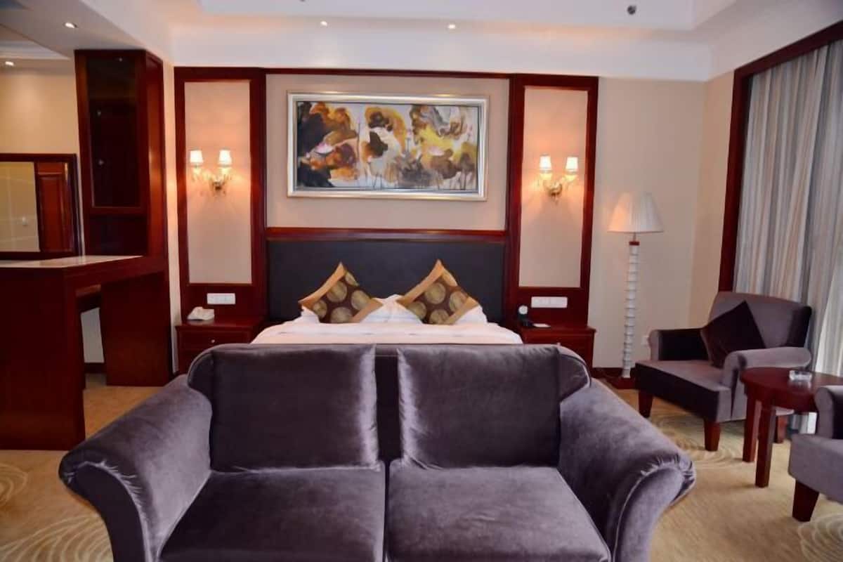 Ein Hotelzimmer mit einem großen Bett, einem Sofa, einem Schreibtisch und einem Gemälde an der Wand.