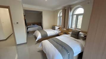 Habitación de hotel con dos camas, cabecero de madera, un escritorio pequeño y una ventana con cortinas.