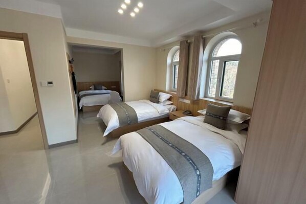 A hotel room with two beds, a wooden headboard, a small desk, and a window with curtains. - Haiyi Hotel Xueye (Jinan)