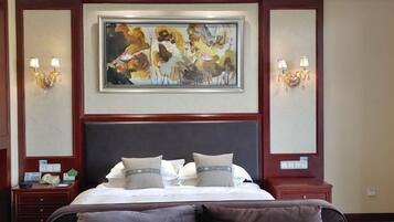 A hotel room with a large bed, two bedside tables, a painting above the bed, and wall sconces.