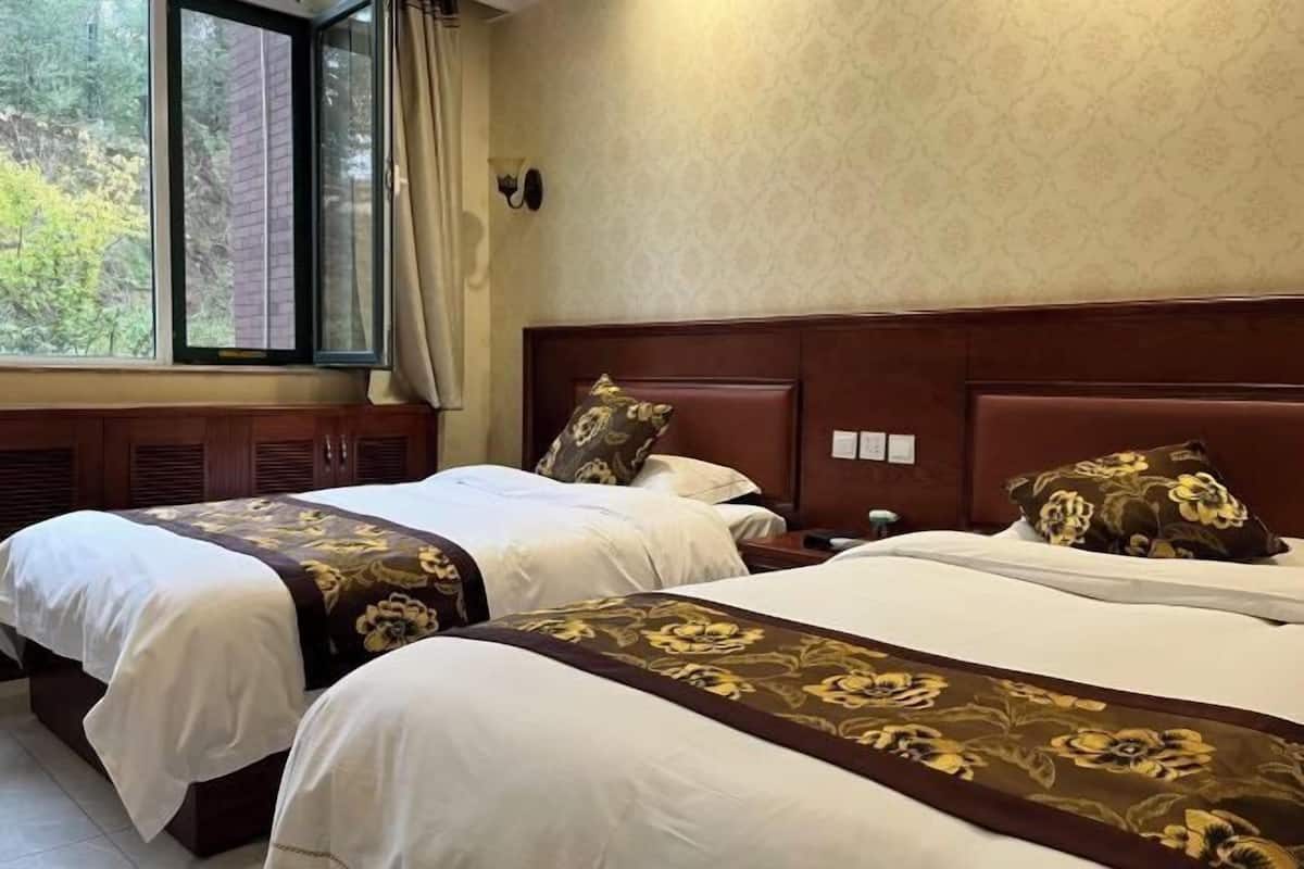 Ein Hotelzimmer mit zwei Betten, einem großen Fenster und einer Wandleuchte.
