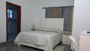 A bedroom with a bed, bedside table, and a desk. - Complejo Ecoturistico Rancho Cielo (Licey al Medio)