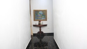 A narrow hallway with a black marble floor, white walls, and a wooden console table with a framed painting above it. - Complejo Ecoturistico Rancho Cielo (Licey al Medio)