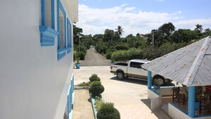 A white building with blue trim, a parked white pickup truck, and a covered outdoor seating area with potted plants. - Complejo Ecoturistico Rancho Cielo (Licey al Medio)