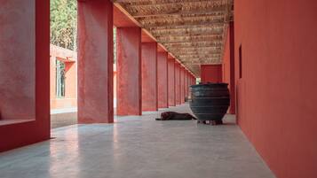 A corridor with red walls and a large black pot in the center.
