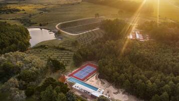 Vue aérienne d’une propriété dotée d’un court de tennis, d’une piscine et d’une grande étendue d’eau.