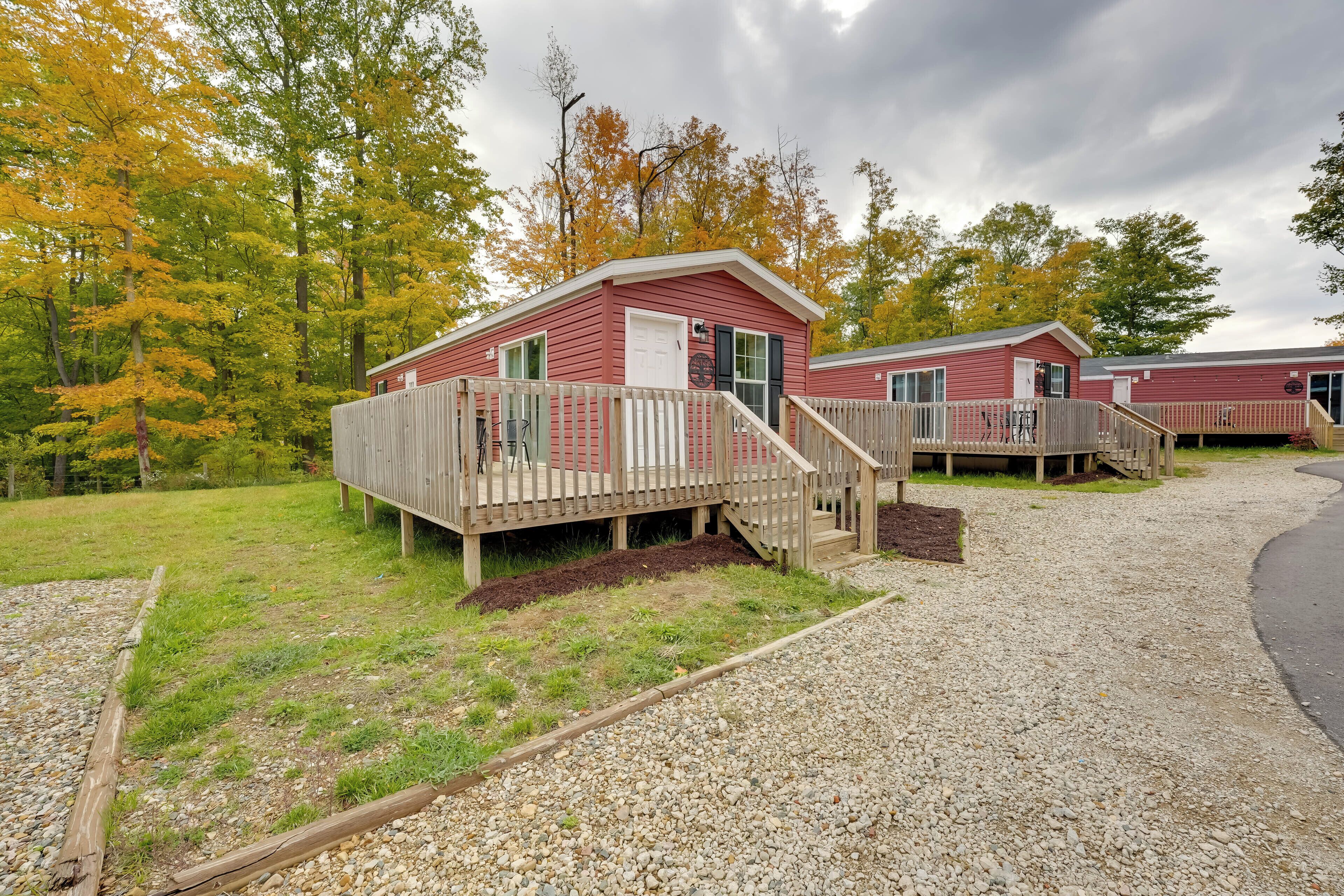Une cabane rouge avec une terrasse en bois et un chemin de gravier menant à celle-ci.