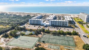 Un hôtel situé sur la côte, composé de plusieurs bâtiments, doté d’un parking et de courts de tennis.