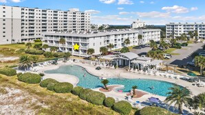 Un resort con varias edificaciones blancas, una piscina central y palmeras.